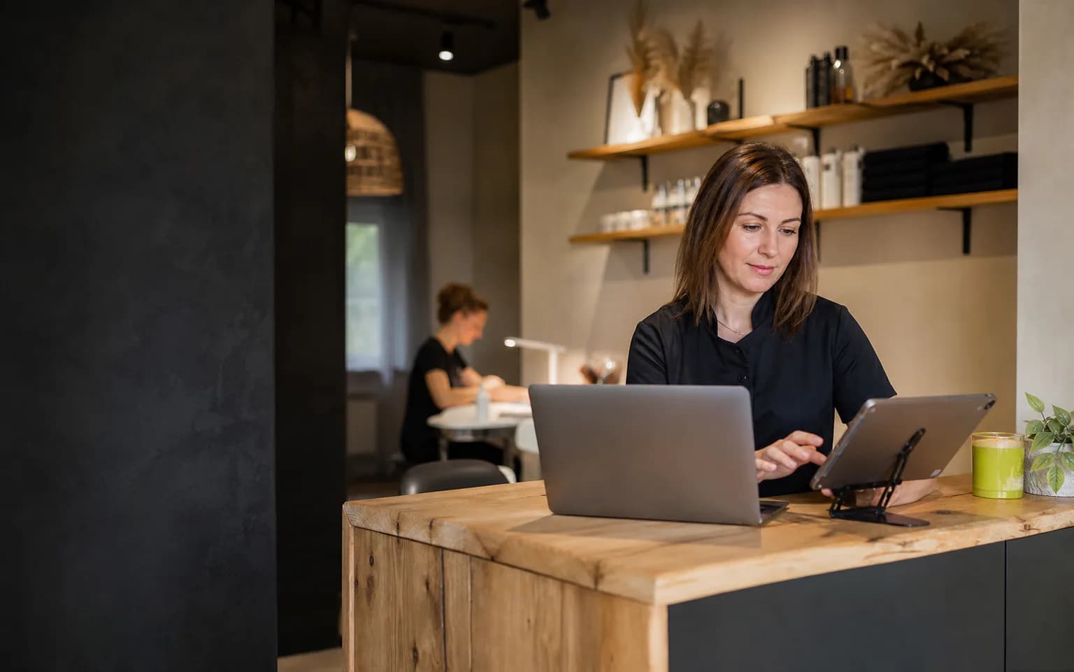 Właścicielka małego salonu zarządza rezerwacjami na laptopie i tablecie